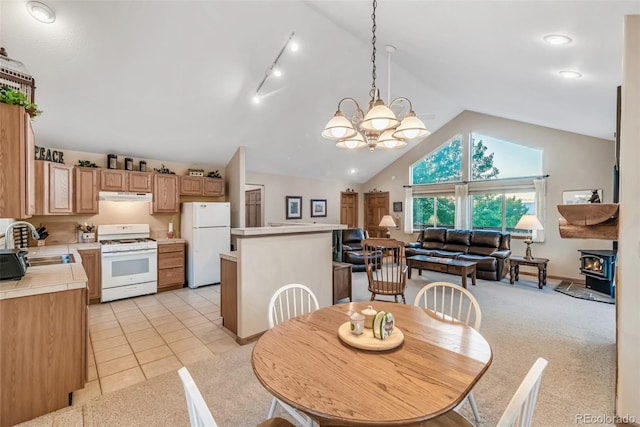 168 Mountain Vis, Como, CO 80432 - dining space featuring a wood stove, vaulted ceiling, light tile patterned floors, light carpet, and a chandelier