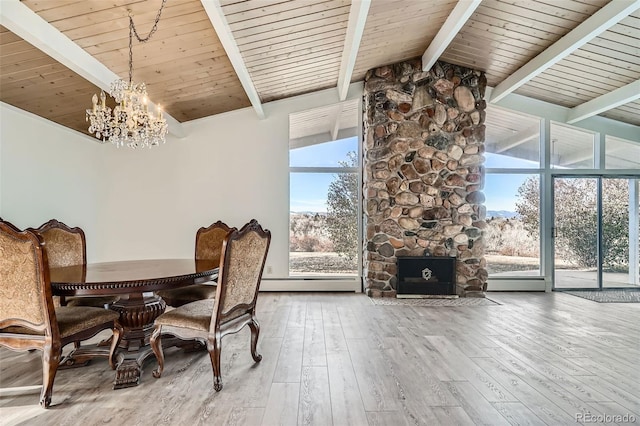 dining area featuring hardwood / wood-style floors, lofted ceiling with beams, a fireplace, a notable chandelier, and wood ceiling