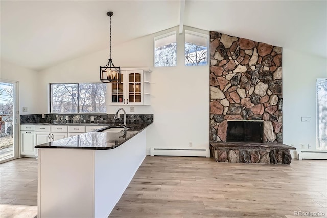 kitchen featuring kitchen peninsula, sink, a baseboard radiator, a fireplace, and hanging light fixtures