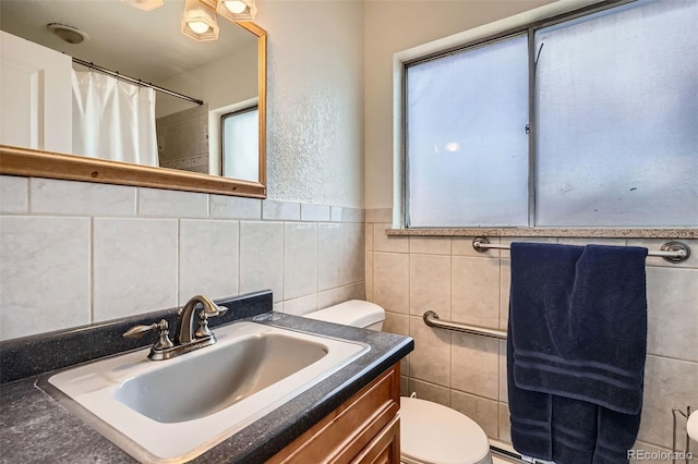 bathroom featuring walk in shower, vanity, tile walls, and toilet