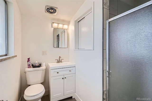 bathroom featuring a shower with door, vanity, and toilet