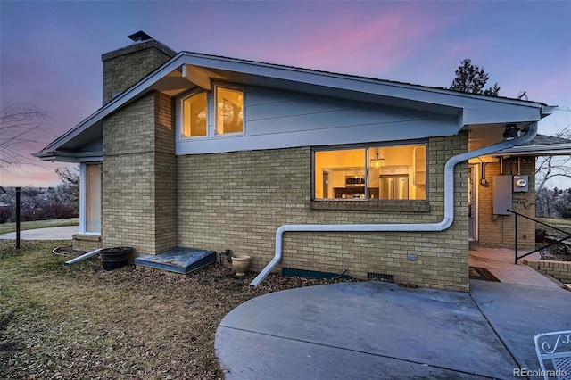 property exterior at dusk featuring a patio area