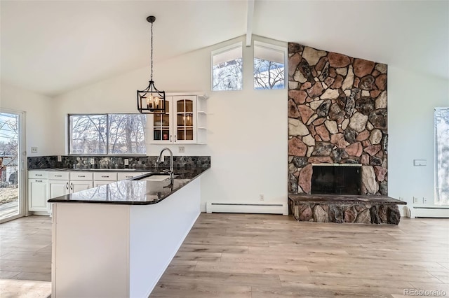 34 S Raleigh St, Denver, CO 80219 - kitchen featuring baseboard heating, dark countertops, white cabinets, a peninsula, and light wood finished floors