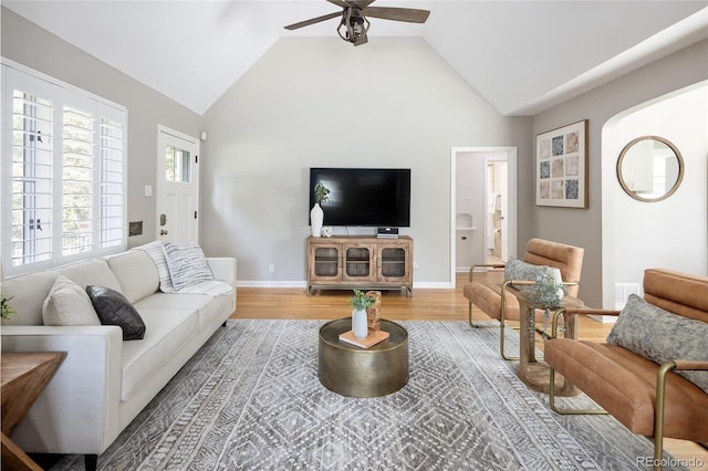 living area with a ceiling fan, baseboards, vaulted ceiling, and light wood-type flooring