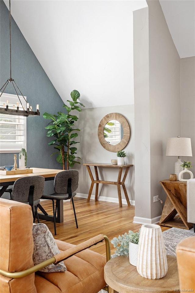 interior space with baseboards, high vaulted ceiling, wood finished floors, and a chandelier