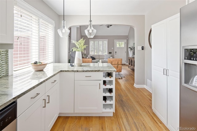 kitchen featuring dishwasher, arched walkways, white cabinetry, open shelves, and light wood-style floors
