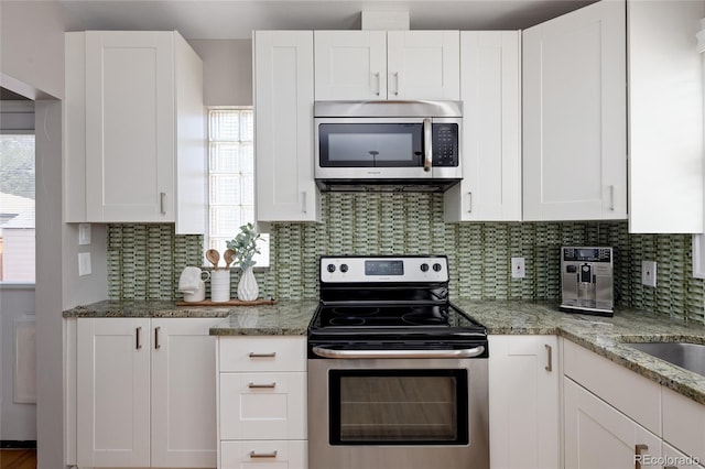kitchen featuring white cabinetry, backsplash, light stone countertops, and appliances with stainless steel finishes