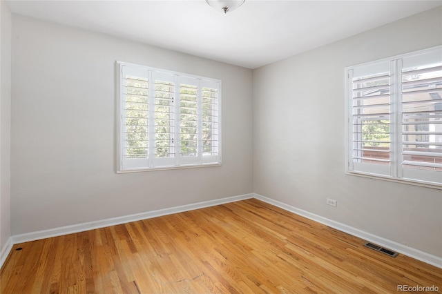 unfurnished room featuring light wood-style flooring, a wealth of natural light, baseboards, and visible vents