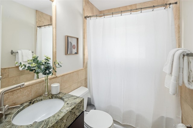 full bath featuring tile walls, toilet, vanity, and wainscoting
