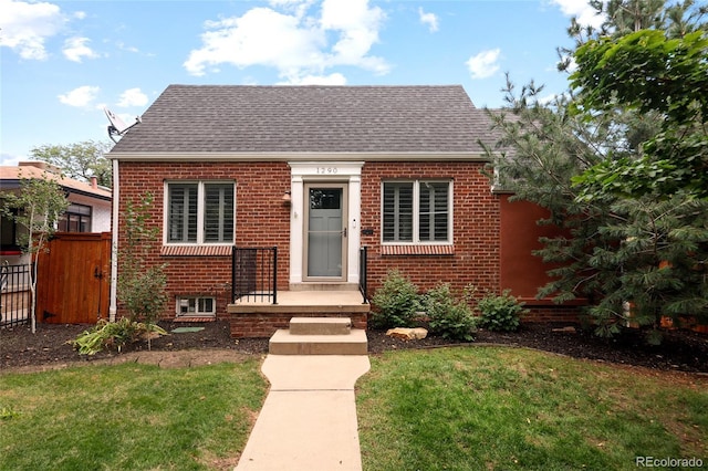bungalow with brick siding, fence, a front lawn, and roof with shingles