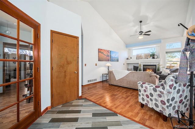 bedroom with a tile fireplace, ceiling fan, wood-type flooring, and vaulted ceiling