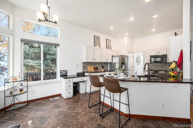 kitchen with white cabinets, stainless steel fridge, a healthy amount of sunlight, and sink