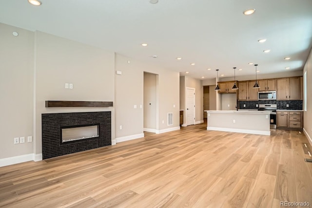 2404 W 69th Pl, Denver, CO 80221 - unfurnished living room featuring light wood finished floors, a tiled fireplace, and recessed lighting