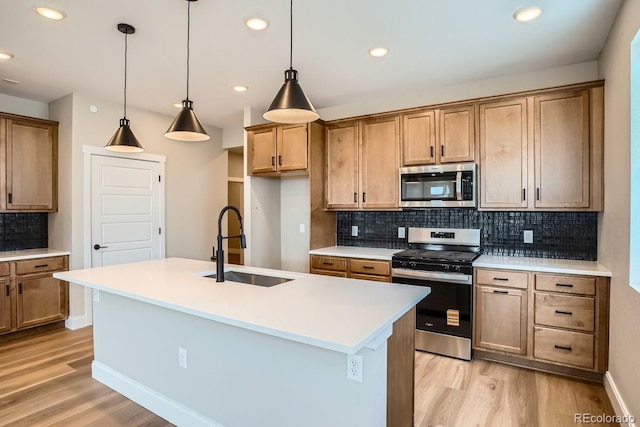 2404 W 69th Pl, Denver, CO 80221 - kitchen featuring appliances with stainless steel finishes, light wood-style floors, tasteful backsplash, a kitchen island with sink, and light countertops