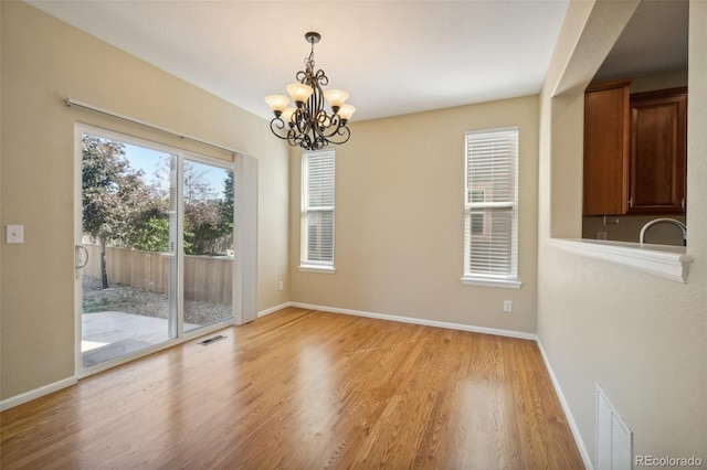 unfurnished dining area with light hardwood / wood-style floors, sink, and an inviting chandelier