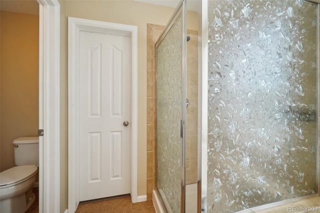 bathroom featuring tile patterned flooring, toilet, and an enclosed shower