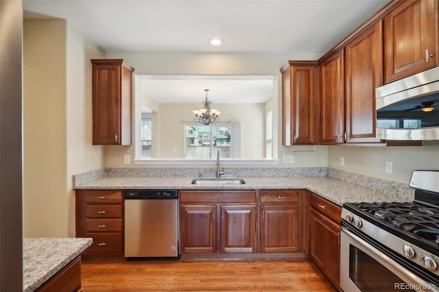 kitchen featuring light stone counters, sink, light hardwood / wood-style flooring, and appliances with stainless steel finishes