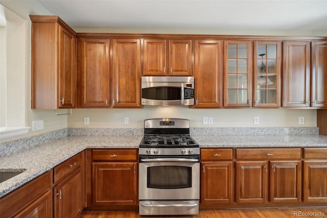 kitchen with light stone counters, stainless steel appliances, and light hardwood / wood-style flooring