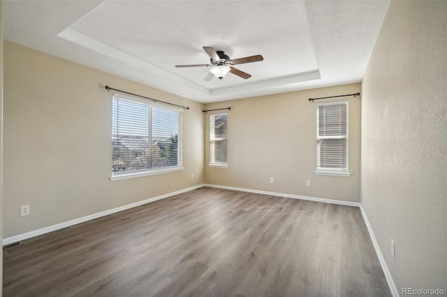 spare room featuring hardwood / wood-style floors, a tray ceiling, and ceiling fan