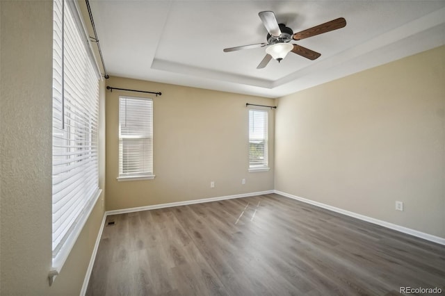 unfurnished room with a tray ceiling, ceiling fan, and wood-type flooring