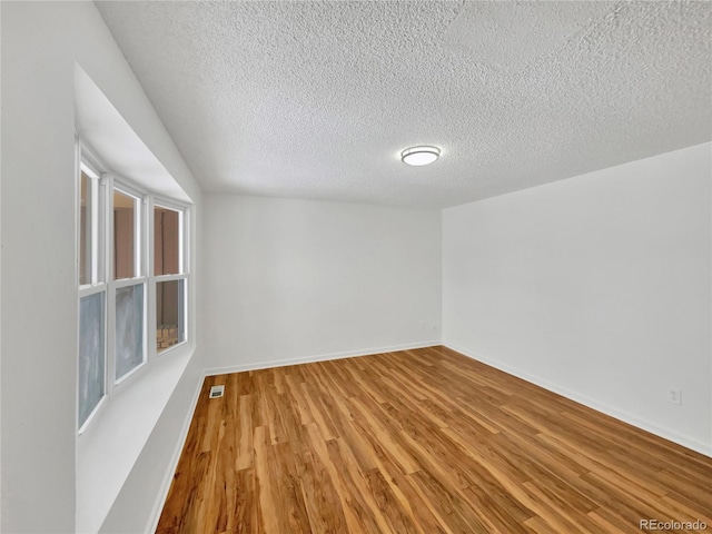 spare room featuring a textured ceiling and hardwood / wood-style flooring