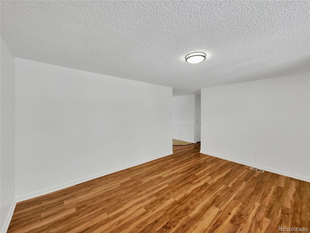 unfurnished room featuring light hardwood / wood-style flooring and a textured ceiling