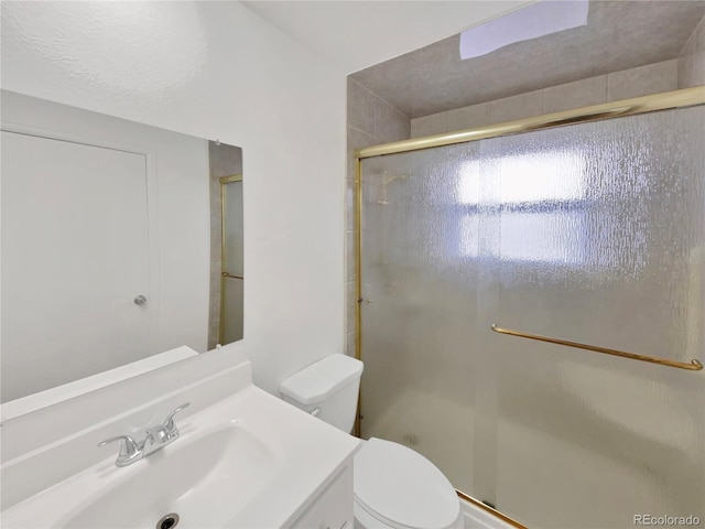 bathroom with toilet, a shower with door, and vanity