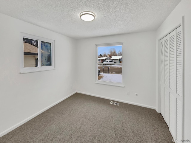 unfurnished bedroom with carpet flooring, a textured ceiling, and a closet