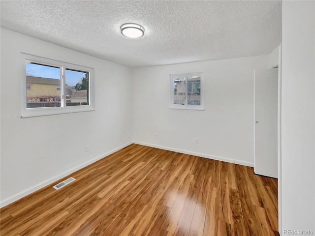 empty room with light hardwood / wood-style floors and a textured ceiling