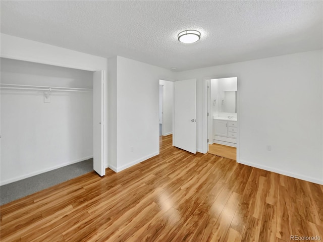 unfurnished bedroom with light hardwood / wood-style flooring, ensuite bath, a textured ceiling, and a closet