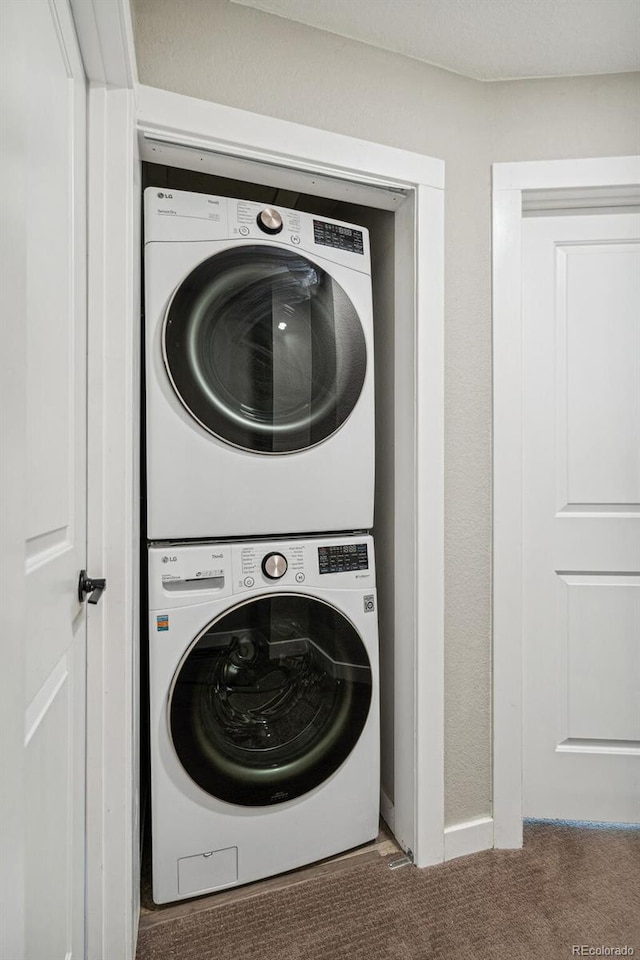 clothes washing area with stacked washer and clothes dryer and carpet floors