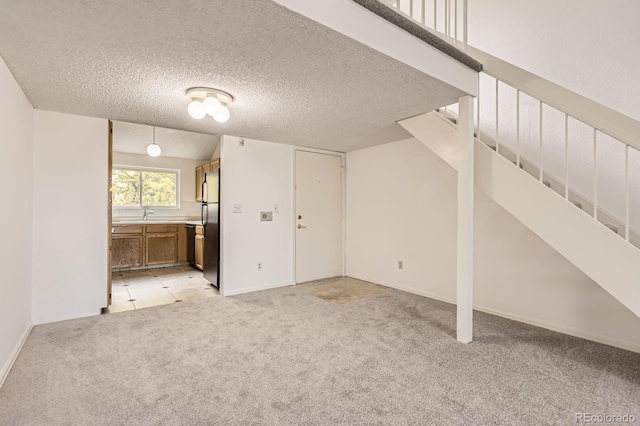 3558 S Depew St Unit 302, Denver, CO 80235 - basement featuring freestanding refrigerator, light carpet, stairs, a sink, and a textured ceiling