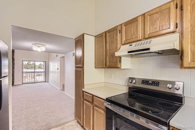 3558 S Depew St Unit 302, Denver, CO 80235 - kitchen with under cabinet range hood, stainless steel electric range oven, light colored carpet, light countertops, and decorative backsplash