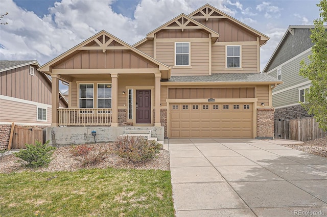 craftsman house with fence, an attached garage, board and batten siding, concrete driveway, and covered porch