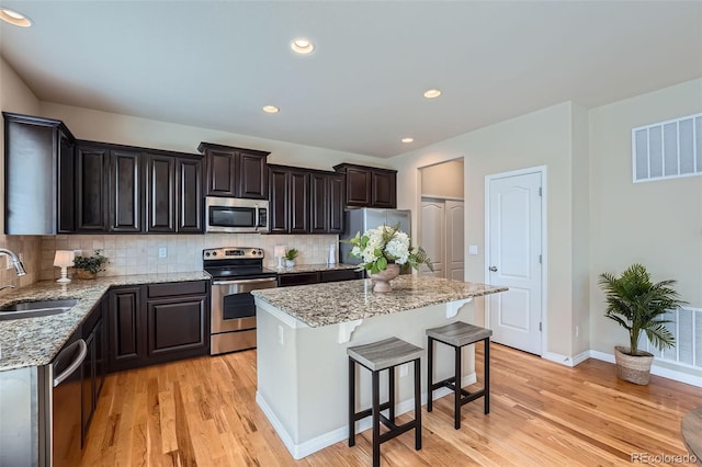 kitchen with a sink, stainless steel appliances, light wood finished floors, and visible vents