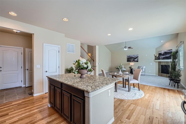 kitchen with visible vents, light wood finished floors, ceiling fan, and a fireplace