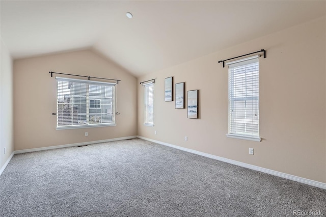 unfurnished room featuring visible vents, baseboards, lofted ceiling, and carpet