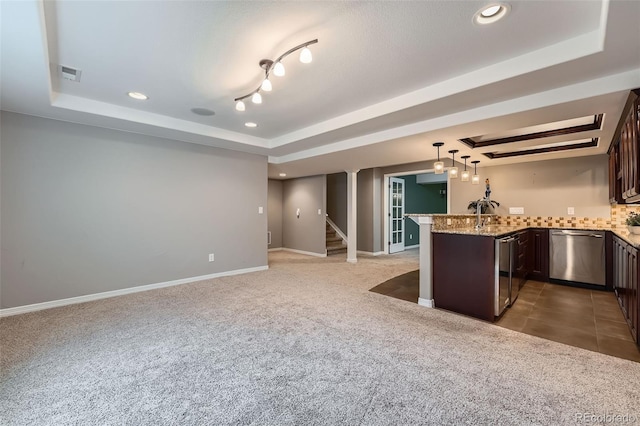 kitchen featuring stainless steel dishwasher, carpet floors, a peninsula, dark brown cabinetry, and a tray ceiling