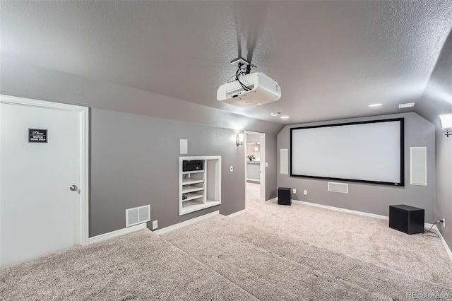 cinema room featuring a textured ceiling, visible vents, vaulted ceiling, built in shelves, and carpet floors