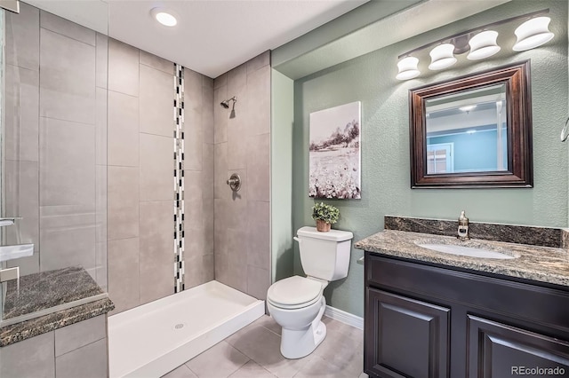 bathroom featuring a textured wall, vanity, toilet, tile patterned floors, and tiled shower