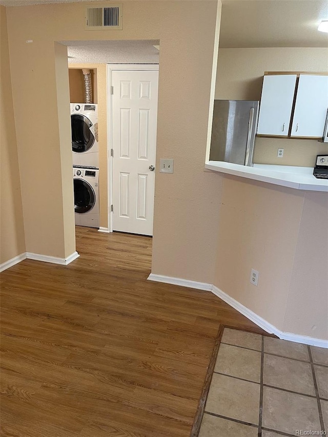 interior space with stacked washer / drying machine and light hardwood / wood-style floors