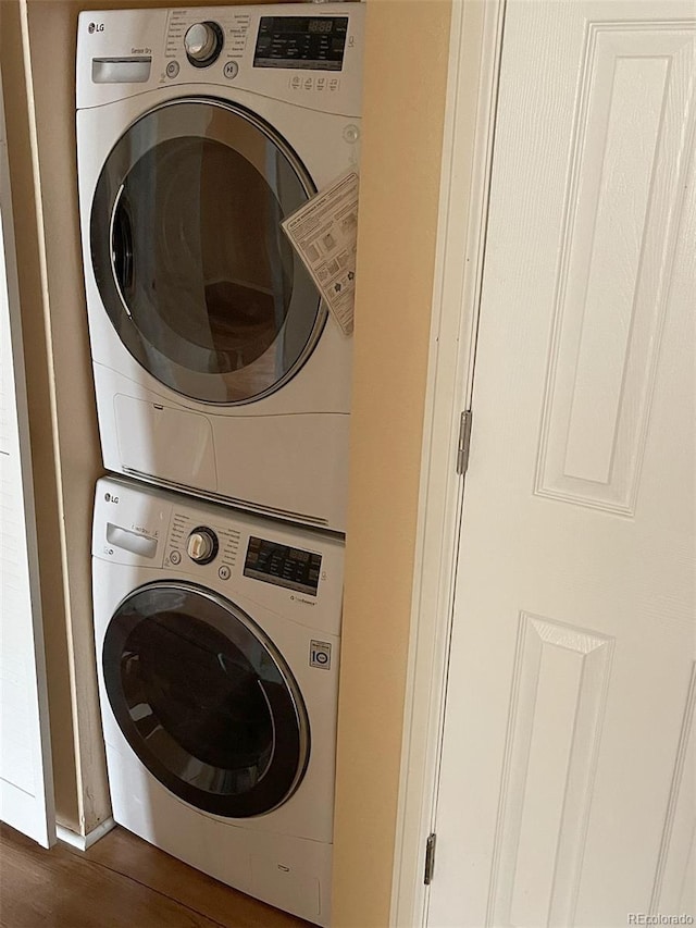 laundry room with stacked washing maching and dryer and dark wood-type flooring