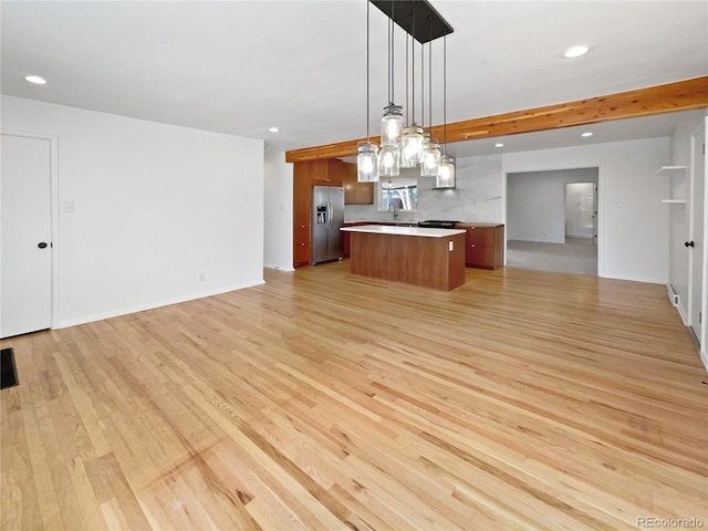 kitchen with a center island, decorative light fixtures, light hardwood / wood-style floors, sink, and stainless steel fridge with ice dispenser