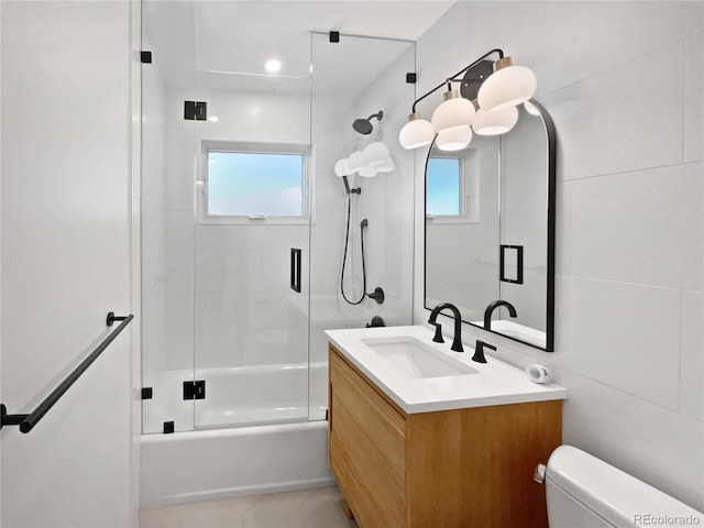 full bathroom featuring bath / shower combo with glass door, toilet, vanity, and tile patterned flooring