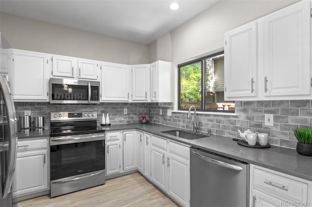 10693 W 63rd Dr Unit 106, Arvada, CO 80004 - kitchen with appliances with stainless steel finishes, a sink, dark countertops, white cabinetry, and recessed lighting