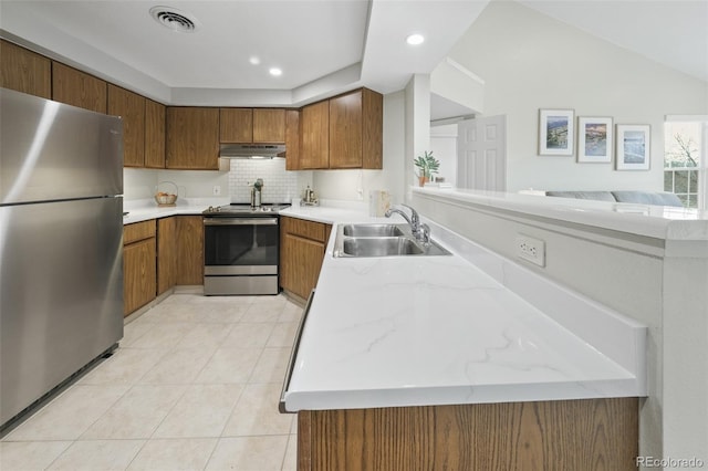 kitchen featuring appliances with stainless steel finishes, sink, decorative backsplash, light tile patterned floors, and kitchen peninsula