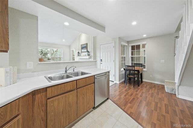 kitchen with lofted ceiling, dishwasher, sink, and light hardwood / wood-style flooring