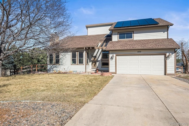 view of front of house with an attached garage, fence, driveway, roof mounted solar panels, and a front yard