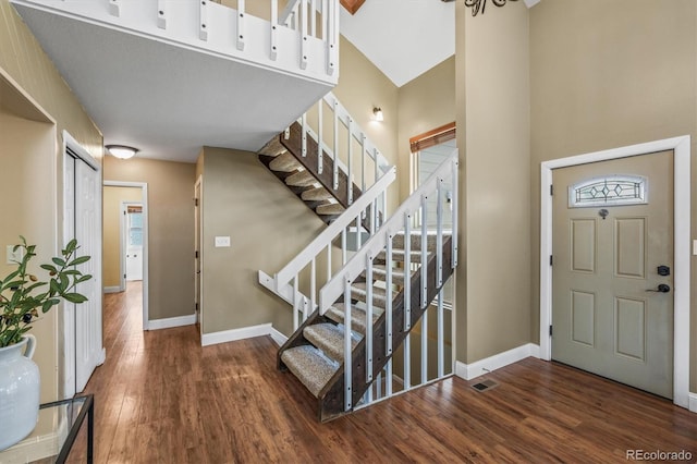 foyer entrance featuring stairway, visible vents, baseboards, and dark wood-style flooring