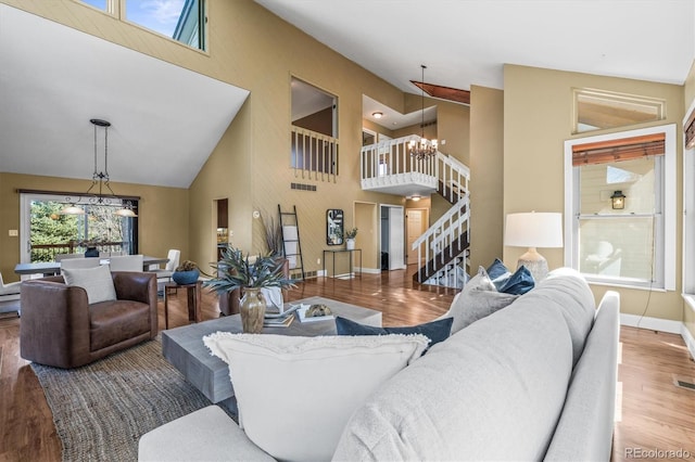 living area featuring lofted ceiling, wood finished floors, a chandelier, baseboards, and stairs